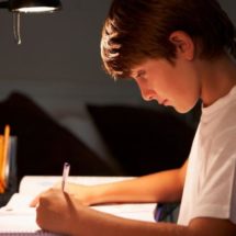Chico estudiando en su escritorio con una correcta iluminación de flexo y luz neutra